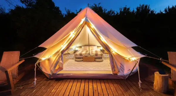 Mysig glampingtält med säng och belysning, redo för en vistelse på nynäshamn camping.