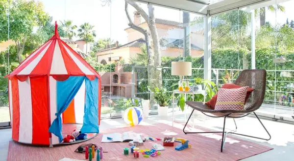 Tienda de circo y juguetes para disfrutar de juegos de patio en un espacio acristalado con vistas al jardín.