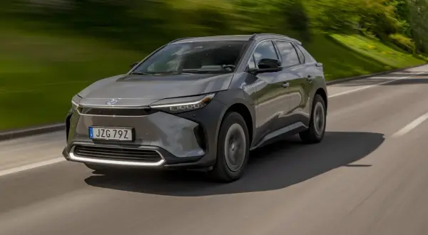 Grå Toyota bZ4X kör på en väg, med grönskande natur i bakgrunden. Ett potentiellt toyota bz4x problem kan vara dess räckvidd.