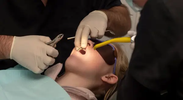 Bambina con apparecchio fisso, forse un po' di dolore nei primi giorni, mentre il dentista lavora sui suoi denti.