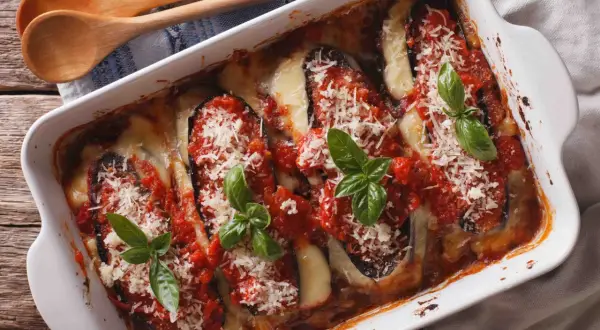 Un plat de parmigiana sicilienne tout juste sorti du four, avec des aubergines, de la sauce tomate, du fromage fondant et du basilic frais.