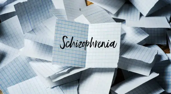 Rozrzucone kartki w kratkę, na jednej napis "Schizophrenia". Symbol chaosu myśli, jak w schizofrenii hebefrenicznej.