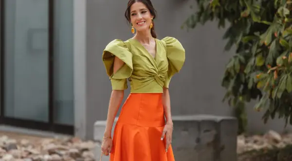 Elegante look invitada boda otoño: top verde con volantes y falda naranja.
