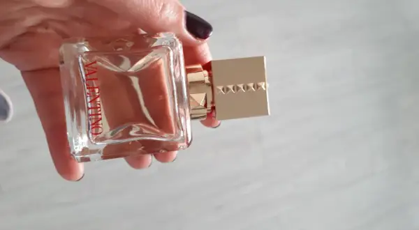 Elegancki flakon Valentino Voce Viva 100ml w dłoni, z charakterystycznym złotym korkiem ozdobionym ćwiekami.