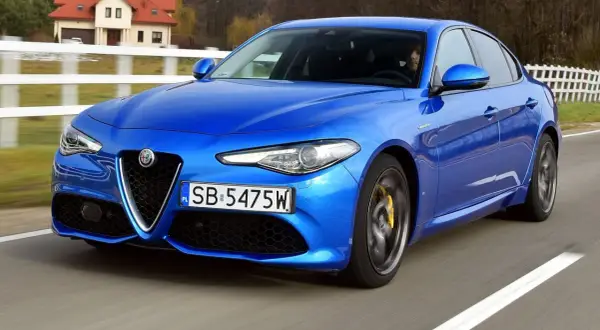 Niebieskie Alfa Romeo Giulia w ruchu. Wiele pozytywnych alfa romeo giulia opinie potwierdza jej sportowy charakter.