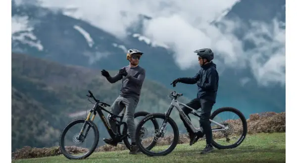 Dos ciclistas con cascos y bicicletas ebike en un paisaje montañoso, listos para explorar nuevas rutas.