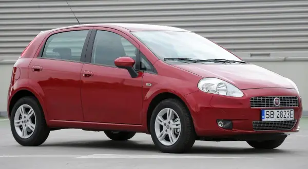 Czerwony Fiat Grande Punto, przód. Wymiana żarówki w reflektorze przednim jest prosta.
