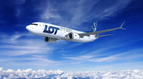 Samolot LOT Polish Airlines leci na tle błękitnego nieba z chmurami.