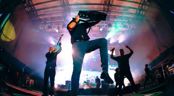 Energetyczny koncert Dropkick Murphys. Muzyk gra na akordeonie, inny na banjo, tłum szaleje.
