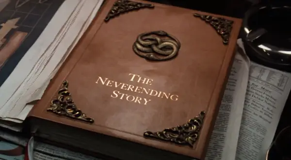 Brązowa księga z napisem "The Neverending Story" i wężami oplatającymi się na okładce.