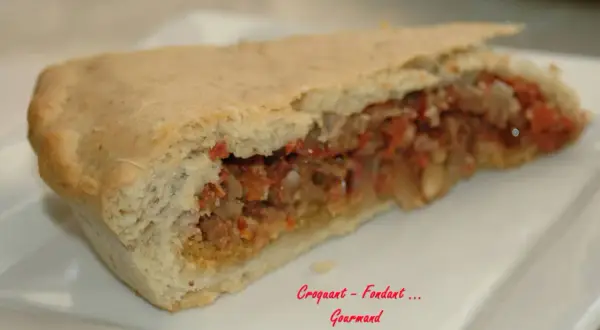 Une part d'impanata siciliana, une tourte sicilienne garnie d'une farce savoureuse, sur une assiette blanche.