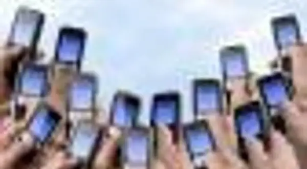 Ręce trzymają telefony komórkowe, gotowe do wysłania pustego SMS-a na loterię.