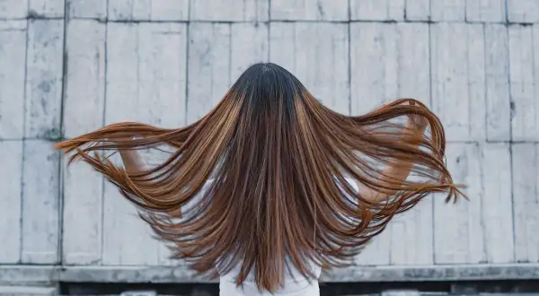 Lange, braune Haare mit honigfarbenen Strähnen, die sich im Wind bewegen. Ein perfekter Look für die sommer trend haarfarben.