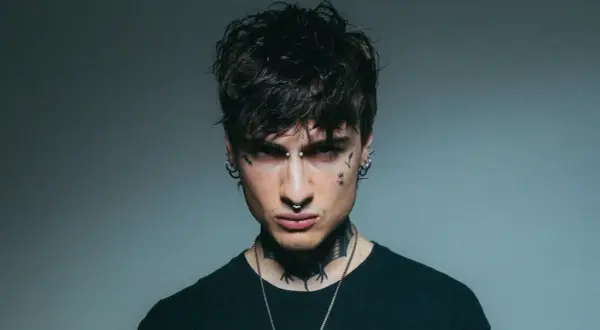 Giovane uomo con piercing e tatuaggi, sguardo intenso, un'aura che ricorda la **rosa chemical**.