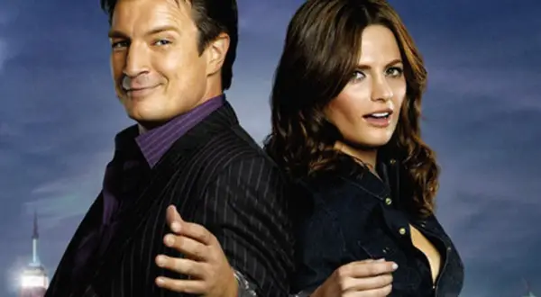 Die besetzung von Castle: Nathan Fillion und Stana Katic, mit Handschellen gefesselt, vor einer nächtlichen Skyline.