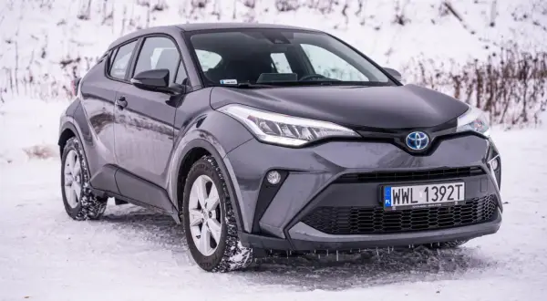 Szary Toyota C-HR Hybrid na śniegu, gotowy na zimowe wyzwania.