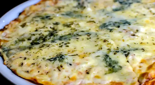 Eine köstliche quattro formaggi pizza mit geschmolzenem Käse und Kräutern, serviert auf einem weißen Teller.