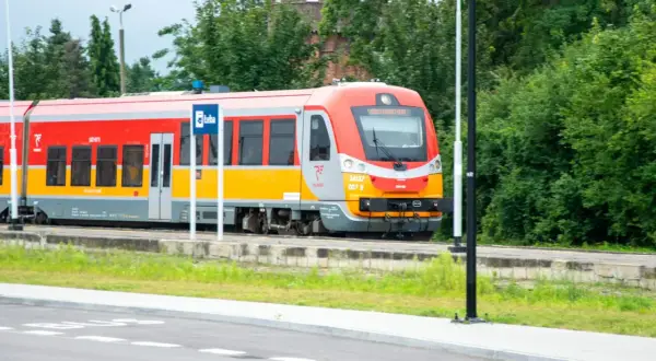 Czerwono-żółty pociąg Polregio na tle zieleni. Czy w Polregio jest rezerwacja miejsc?