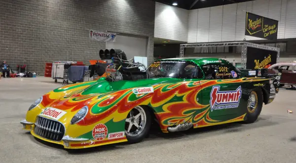 Une voiture de dragster aux couleurs vives, un exemple de tuning extrême, avec un moteur surdimensionné et des flammes peintes.