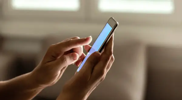 Dłonie trzymają smartfon, na którym można sprawdzić ile lat ma telefon.
