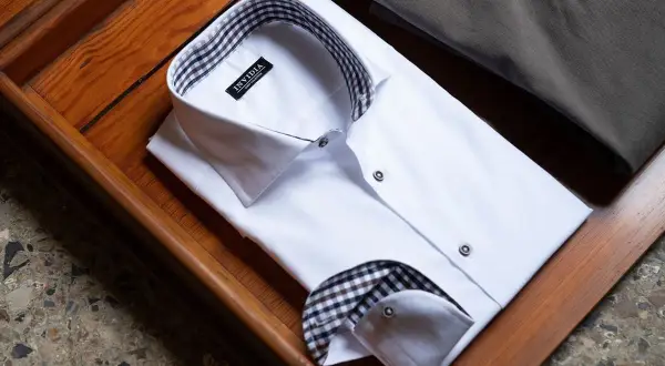 Camicia bianca da uomo con colletto e doppio polsino a quadri marroni e neri, pronta per un'occasione speciale.