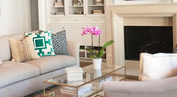 A sofa with pillows showcasing mixing patterns: a fawn print, a bold green geometric, and a black and white ikat.