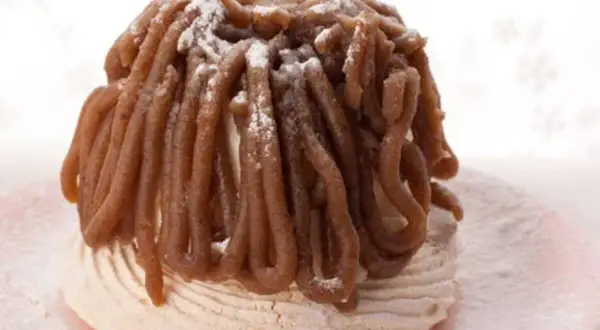 Delicioso mont blanc dulce, un postre de merengue cubierto con crema de castañas y espolvoreado con azúcar glas.
