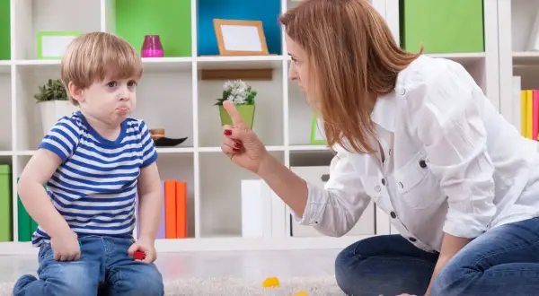 Mamma che si arrabbia con i figli piccoli, puntando il dito contro il bambino che fa il broncio.