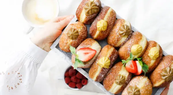 Frisch gebackene Faschingskrapfen mit Puderzucker, Erdbeeren und einer Tasse Kaffee. Ein Genuss zum Fasching!