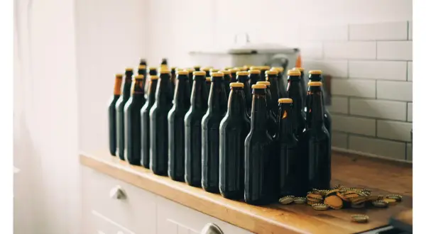 Rząd ciemnych butelek piwa, gotowych do degustacji. Zestaw brewkit Coopers czeka na otwarcie.