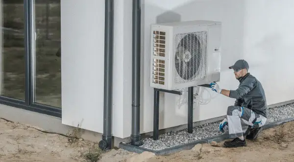Tecnico che installa una pompa di calore esterna, un sistema efficiente per riscaldare e raffreddare la casa.