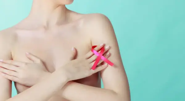 Kobieta z różową wstążką na piersi, symbol walki z rakiem. Wstążka symbolizuje nadzieję i wsparcie dla osób poszukujących leków na torbiele w piersiach.