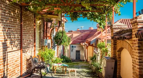 Urokliwa uliczka w Kachetii, Gruzja, z ławką, stołem i winoroślą nad głową.