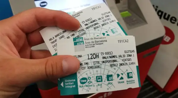 Dłoń trzyma bilety na Barcelona komunikacja miejska. Widać logo TMB i nazwy środków transportu.