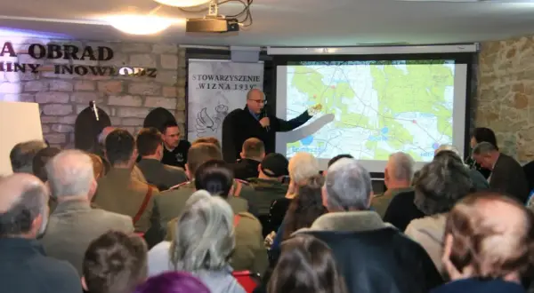 Prezentacja o Hubalu i jego szlaku bojowym. Mężczyzna wskazuje na mapę, a publiczność słucha.