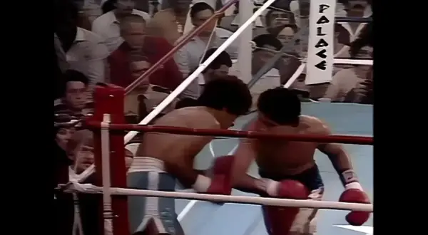 Two boxers, Salvador Sanchez and Wilfredo Gomez, clash in the ring. The crowd watches intently as they exchange blows.