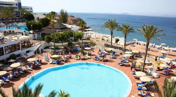 Relaks na basenie w hotelu Sandos, z widokiem na morze i palmami.