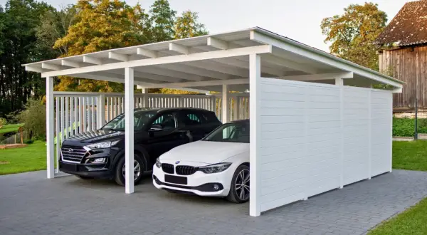 Nowoczesna wiata przy domu chroni dwa samochody: czarnego SUV-a i białe BMW.