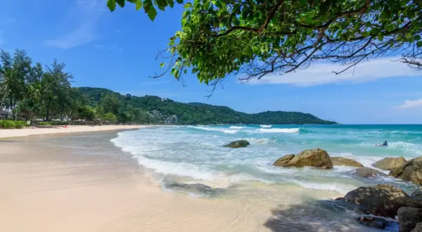 Piękna plaża Kata Beach z turkusową wodą, falami i palmami. Idealne miejsce na relaks.