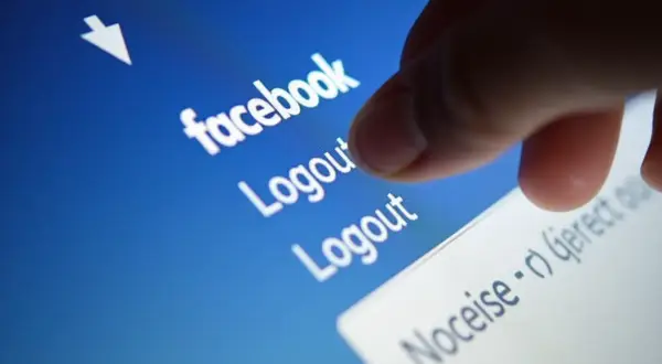 Palec dotyka opcji "Logout" na ekranie telefonu, pokazując, jak wylogować z Facebooka.