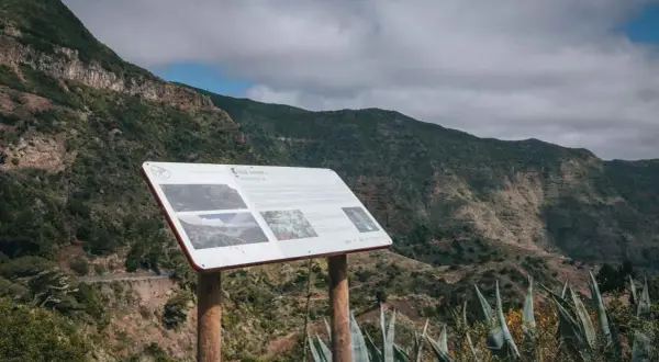 Panel informativo en el mirador de Carboneras, con vistas a un valle montañoso cubierto de vegetación.