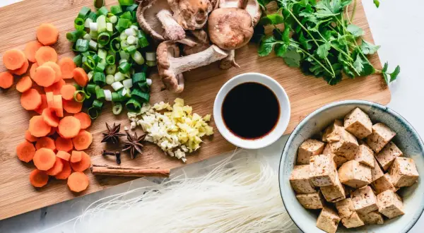 Co jedzą weganie? Tofu, makaron ryżowy, grzyby shiitake, marchew, szczypiorek, czosnek, imbir, kolendra, sos sojowy i przyprawy.