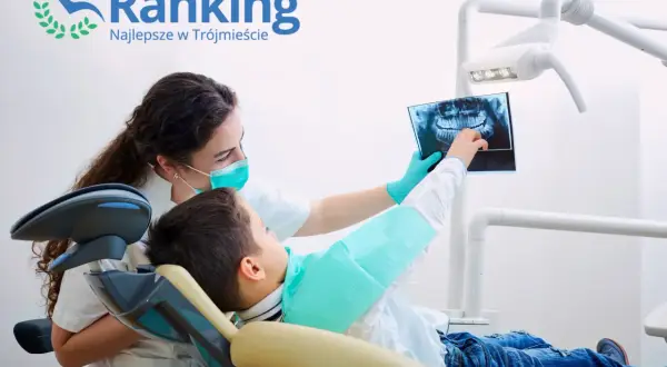 Dentystka w masce pokazuje dziecku zdjęcie rentgenowskie zębów.