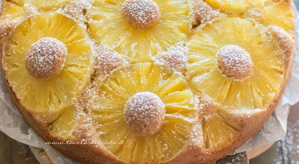 Torta ananas dorata e profumata, decorata con fette di ananas caramellato e spolverata di zucchero a velo.