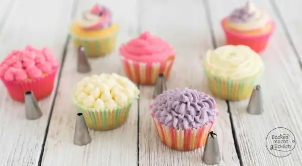 Bunte Cupcakes mit verschiedenen **cupcake topping** Mustern, umgeben von Spritztüllen.