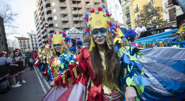 Gente disfrazada con trajes coloridos y elaborados desfila en los carnavales de Zaragoza, celebrando con alegría y arte.