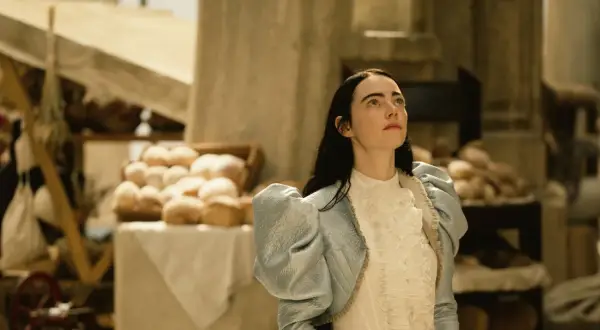 Bella Baxter blickt hoffnungsvoll gen Himmel, während sie auf dem Markt steht. Ein Bild, das Lust macht, "Poor Things" zu streamen.