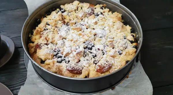 Pyszne kruche ciasto ze śliwkami i kruszonką, posypane cukrem pudrem, czeka na spróbowanie.