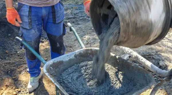 Robotnik wylewa beton B25 z betoniarki do taczki. Sprawdzamy beton B25 cena za m3.