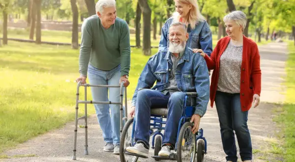 Uśmiechnięci seniorzy spacerują po parku. Warto zabrać do sanatorium w Ustroniu wygodne ubrania i dobry humor.